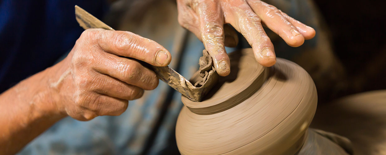 potter working clay with knife